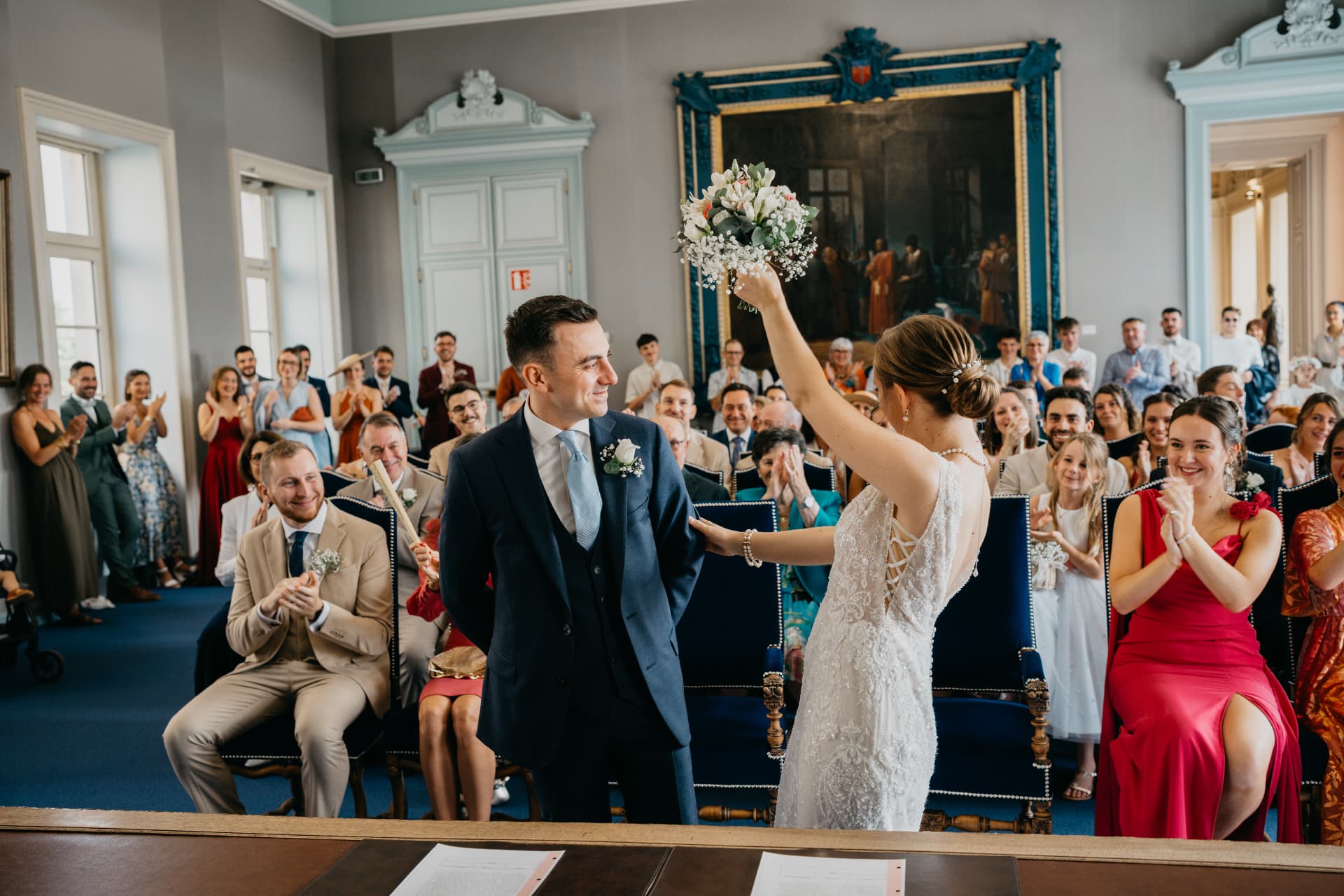 La mariée lève son bouquet devant l'assemblée à la mairie