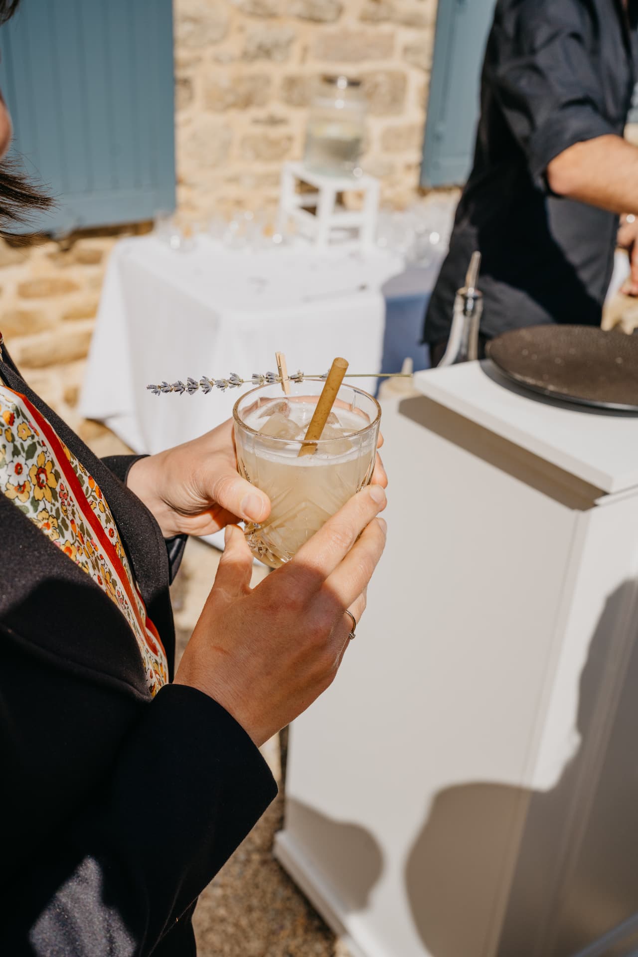 Verre de cocktail garni de lavande tenu à la main pendant le vin d'honneur