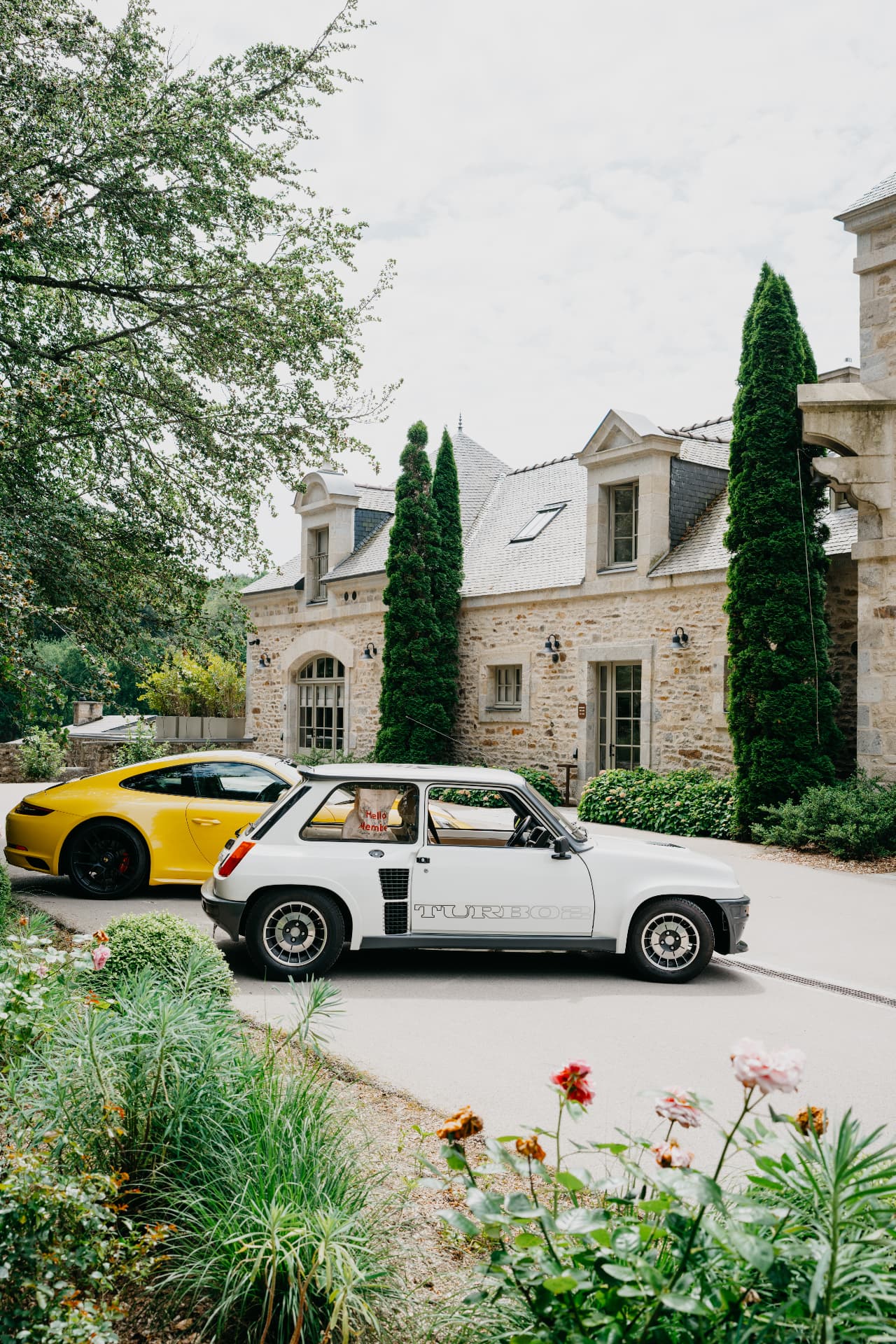 Deux voitures de collection garées devant un manoir de pierre