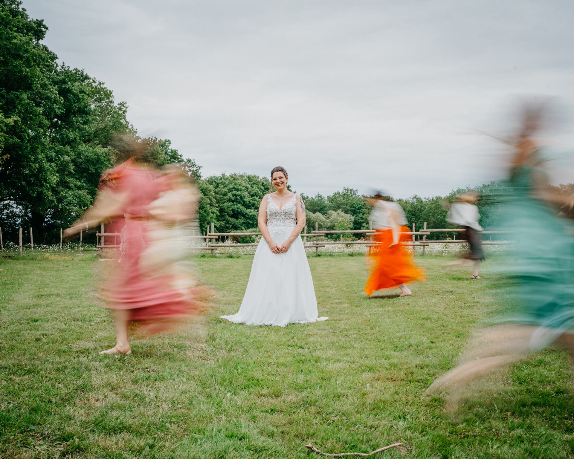 La mariée entourée de ses demoiselles d'honneur en mouvement dans un pré