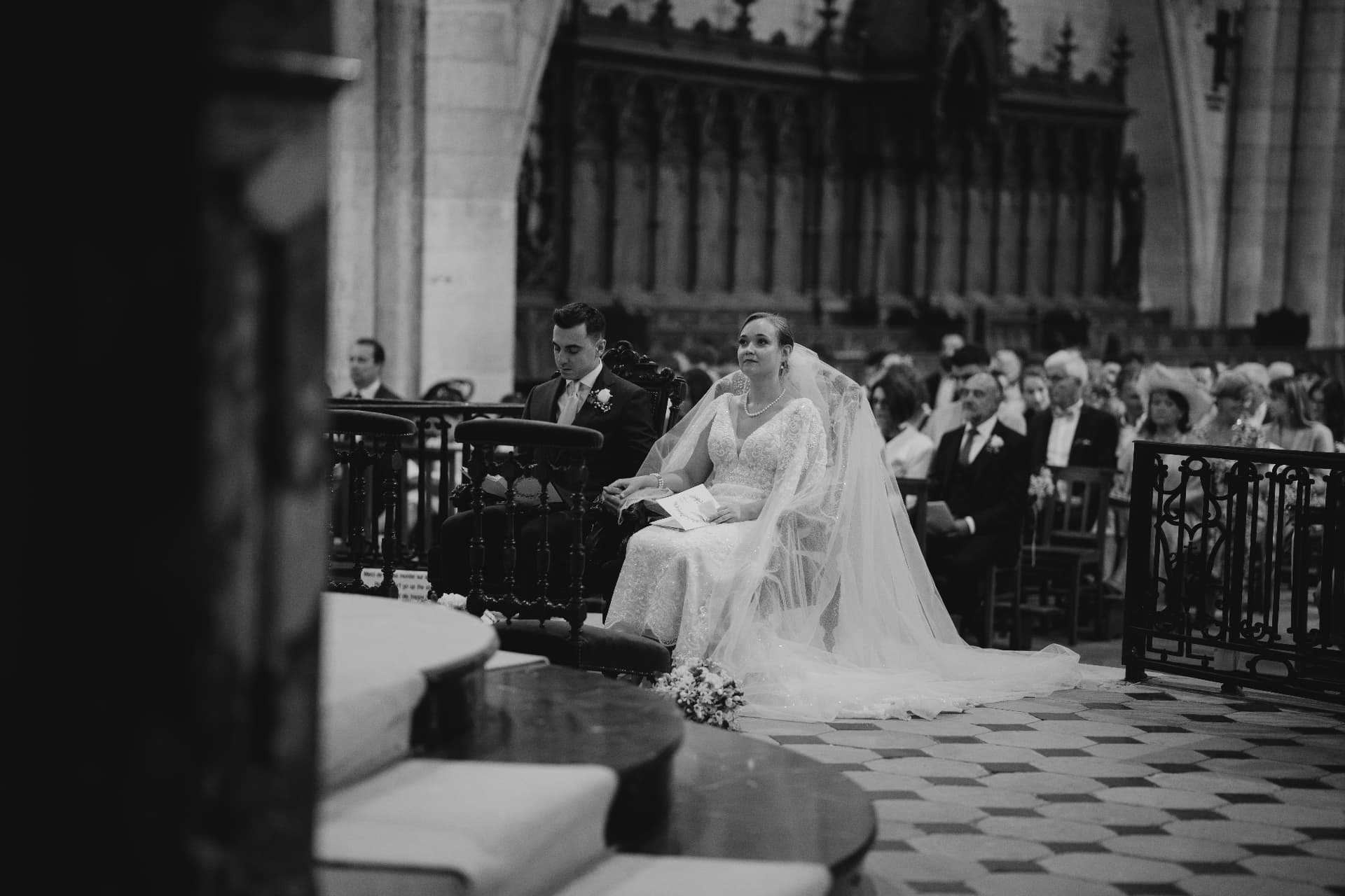 Les mariés assis côte à côte devant l'autel d'une église