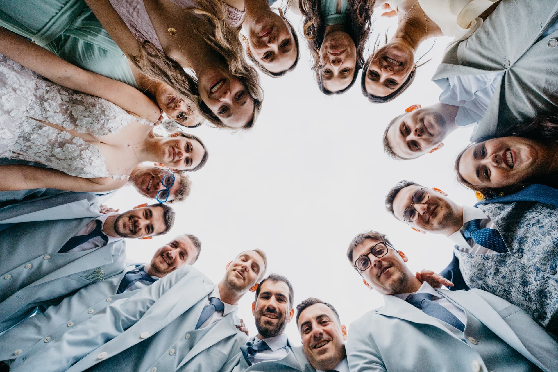 Les mariés et leurs témoins en cercle, vus d'en bas face au ciel