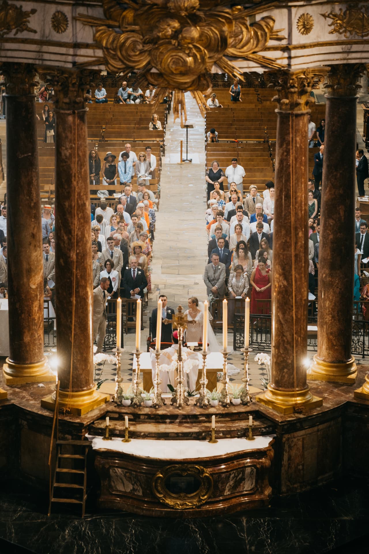 Les mariés devant l'autel entourés de leurs invités dans la nef d'une église