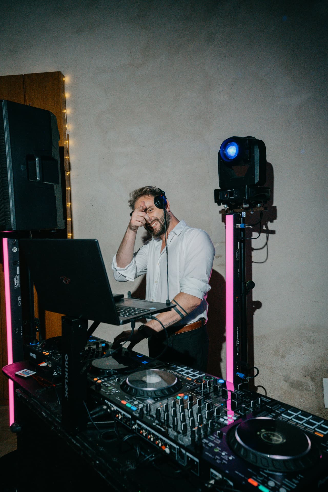 Le DJ SPO, casque sur une oreille, souriant derrière ses platines